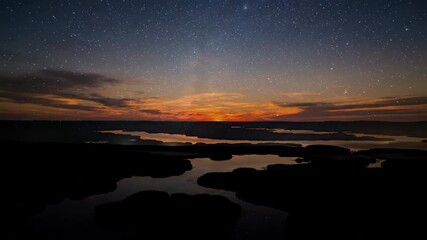 Wall Mural - Holy grail timelapse transitioning from a vibrant day to a star-filled night over a remote marshland water, movement, environment
