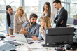 © Bojan - Group of business people gathered around boss with laptop discussing positive business decisions and company development