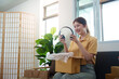© Natee Meepian - Unboxing: Young woman excitedly opening package from online shopping
