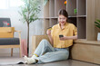 © Natee Meepian - Online Shopping. Young woman enjoying smartphone shopping while sitting on the floor at home.