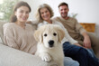© Frank Parker - Family enjoying time together on a sofa with a golden retriever puppy