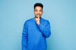 © ViDi Studio - Young man of African American ethnicity wear sweatshirt casual clothes say hush be quiet with finger on lips shhh gesture isolated on plain pastel light blue cyan background studio. Lifestyle concept.