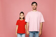 © ViDi Studio - Young smiling happy parent man with child girl she wear red casual clothes. Daddy little kid daughter stand hold hands look camera isolated on plain pink background. Father's Day Love family concept.