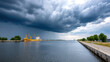 © S.W. - Global logistic transportation concept with yellow cargo ship docked at harbor under dramatic cloudy sky before storm