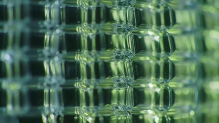 Abstract macro view of a transparent grid structure refracting vibrant green and blue light.