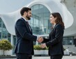 © Ilya - Professional business meeting at modern architectural building featuring handshake