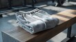 © Queen - Comfortable light grey sweatpants neatly folded on a wooden bench, set against a blurred gym backdrop, symbolizing preparation for activity or relaxed athleisure wear