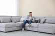 © New Africa - Young man using laptop on sofa at home