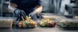 © HelenP - The Salad Packaging Line in a Commercial Kitchen with Gloved Hands Preparing Meals