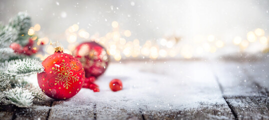 Wall Mural - christmas red decorations on snow with fir tree branches and christmas lights. winter decoration bac
