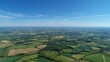 © maxximmm - The landscape showcases expansive fields with diverse fields extending towards the horizon under a striking blue sky. Fields and sky dominate this serene countryside view.