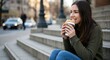 Coffee to go and tasty sandwich enjoyed by woman on city stairs.