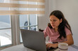 © Guillermo Spelucin - Young woman learning and working remotely using a laptop at home