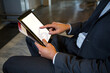 © Wavebreak Media - Adult man wearing business attire tapping tablet by metal bench in modern office lobby, copy space