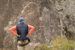 © Wavebreak Media - Senior man planning ascent wearing knit beanie, quilted vest, harness on grassy slope by rock face