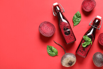 Wall Mural - Bottles of fresh beet juice with basil and vegetables on red background