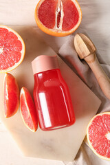 Wall Mural - Board with bottle of tasty grapefruit juice, fresh fruits and juicer on light wooden background