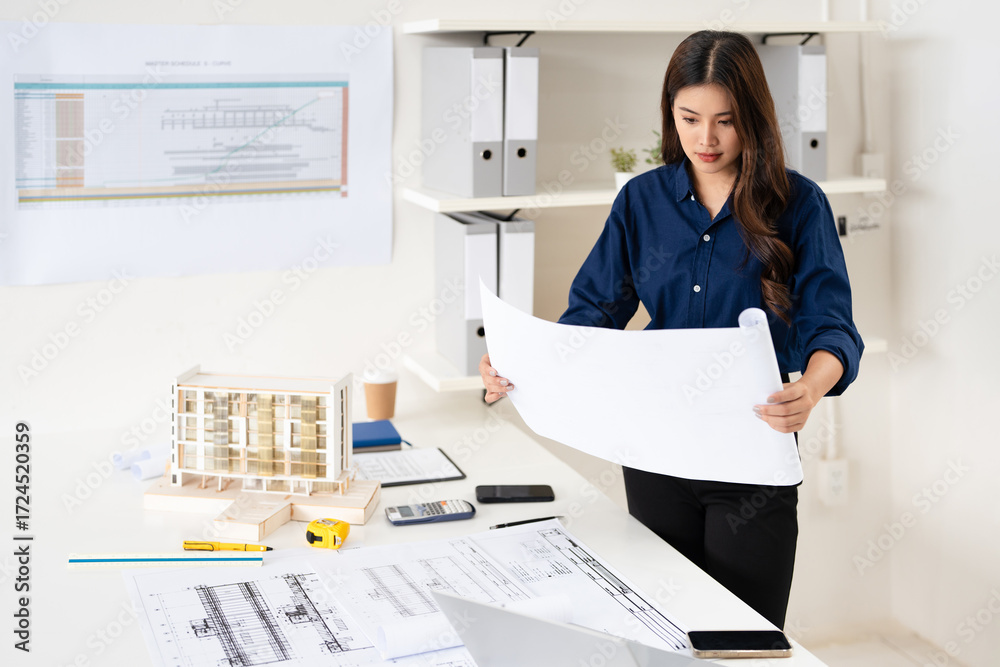 Young asian civil engineer studying a blueprint floor plan and working ...