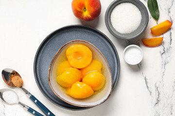 Wall Mural - Composition with bowl of tasty canned peaches and sugar on light background