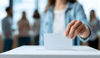 © DodolansStudio - Woman casts ballot into voting box at polling station during election, emphasizing civic duty and democratic process in a modern setting.