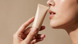 © HunterSnap - A woman's beautiful, soft hand holding a blank beige cosmetic tube