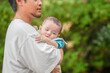 © Masakazu Tokashiki - A man is holding a baby in his arms. The baby is wearing a blue shirt