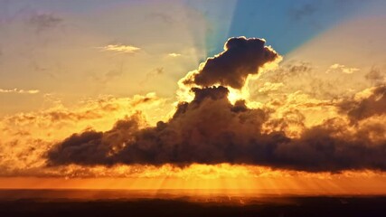 Wall Mural - Towering cloud formation in front of sun casting rays through atmosphere during sunset, aerial timelapse of heavenly hat shape
