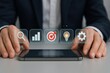 © Haseeb - Businessman using smartphone with floating digital interface icons for search, growth, goals, and ideas