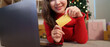 © Natee Meepian - Christmas Online Shopping. Woman holding credit card and smiling at laptop.