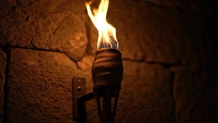 Sticker - timelapse of an ancient-looking torch burning brightly against a dark stone wall, fuel slowly consum