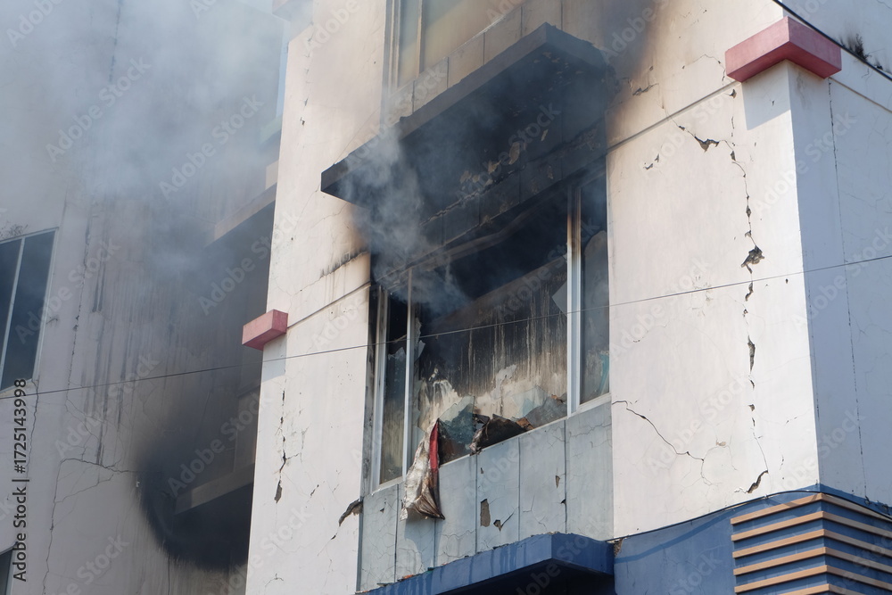 Fire burns through window of building, causing smoke and damage to the ...