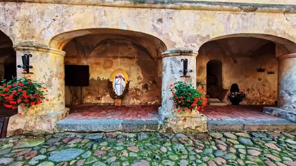 Wall Mural - Cobblestone path into the historic courtyard of Jaunpils Castle, revealing the beautiful and rustic arched arcade of the ancient medieval fortress in Latvia - smooth push-in shot