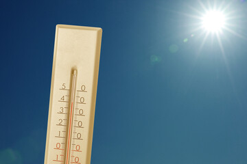 Wall Mural - thermometer showing high temperature against sky with bright sun. extremely hot weather