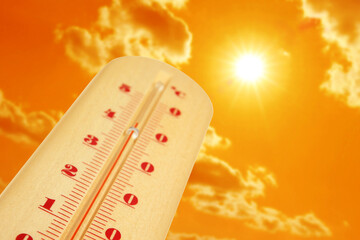 Wall Mural - thermometer showing high temperature against orange sky with bright sun and clouds. extremely hot we