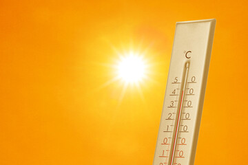 Wall Mural - thermometer showing high temperature against orange sky with bright sun. extremely hot weather