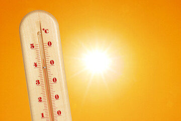 Wall Mural - thermometer showing high temperature against orange sky with bright sun. extremely hot weather