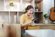 © Natee Meepian - Unboxing Joy. Young woman excitedly opening a package while shopping online.