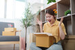 © Natee Meepian - Online Shopping. Woman expressing joy while unboxing a delivery.