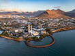 © AmazingAerialAgency - Aerial view of the city's skyline meeting the mountains, with the power plant's white stacks standing out against the blue sea, Port Louis, Port Louis District, Mauritius.