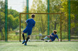 © Mediaphotos - Teenage boy kicking soccer ball toward goal while another teenage boy in goalkeeper position diving to block shot during outdoor soccer match