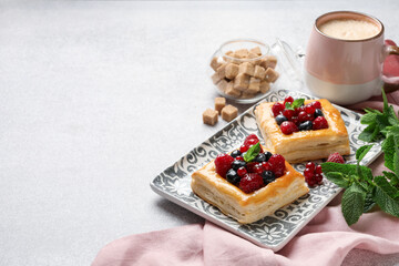Wall Mural - Tasty puff pastries with berries, mint, brown sugar and coffee on light grey table, closeup. Space for text