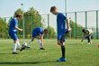 © Mediaphotos - Group of and Black teenagers warming up and stretching on outdoor soccer field before practice, one teenager balancing soccer ball on foot, green fence and trees in background