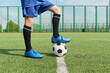 © Mediaphotos - Teenage boy standing on outdoor soccer field placing foot on soccer ball, wearing sports uniform and cleats, preparing for game or practice, lower body visible