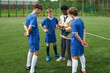© Mediaphotos - Teenage boys standing on soccer field listening to Black male coach explaining strategy using digital tablet during outdoor team practice session