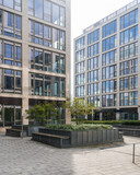 Modern office buildings with glass facades surrounding a courtyard with greenery and seating areas