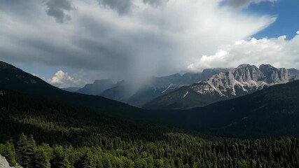 Wall Mural - dramatic clouds and moving shadows sweep across a vast mountain forest landscape in an epic timelaps