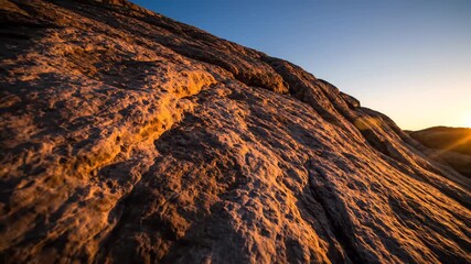 Wall Mural - abstract timelapse of long shadows slowly stretching and shifting across a textured rock formation a