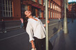 © BullRun - Joyful woman smiles leaning on pole outdoors in sunlight. Conceptual stock photo symbolizing empowerment, individuality, confidence, and authenticity in modern urban lifestyle identity.