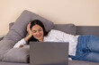 © Midea  - The woman is relaxing on a sofa while looking at a laptop