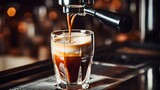 Espresso shot being poured into glass cup from espresso machine for coffee drink preparation at cafe